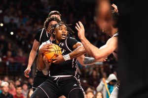 South Carolina Gamecocks basketball player drives to the basket while being defended during a college basketball game.