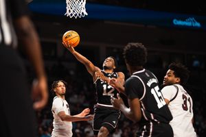 South Carolina Gamecocks player number 12 attempts a layup during a college basketball game in a packed arena.