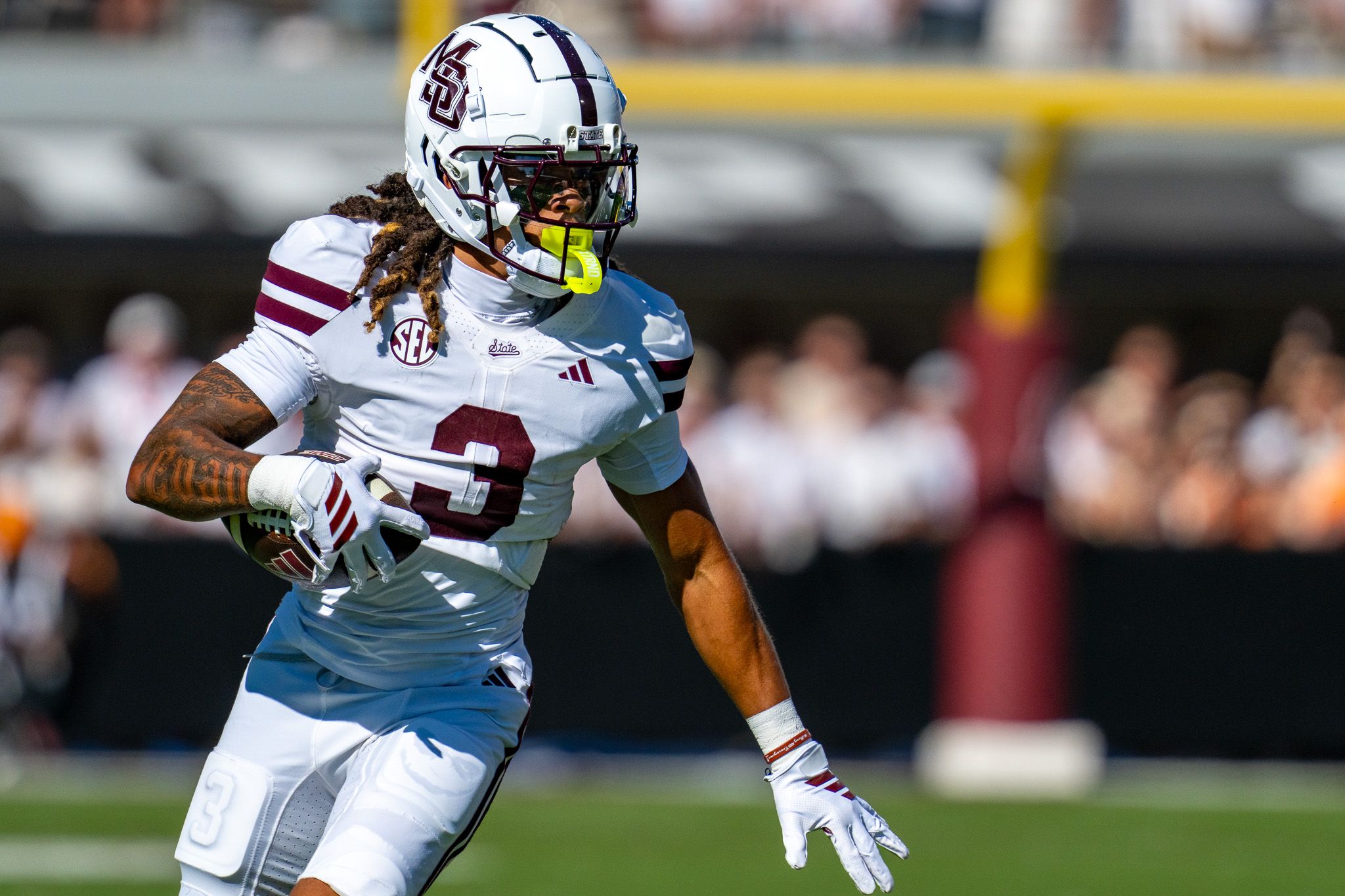 Players in white uniforms prepare for the next play during a college football game.