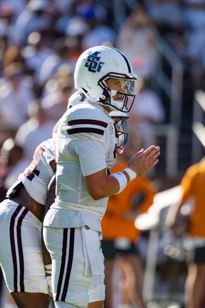 College football players in white uniforms huddle together during a game.