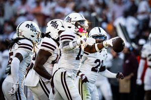 College football players in white uniforms celebrate together during a game.