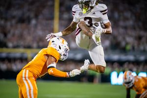 Football players in orange and white uniforms clash during an intense play.