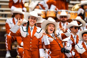 Texas Longhorns band members in orange uniforms perform during a game.