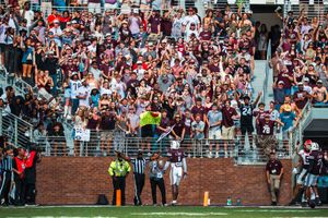 Packed stadium crowd watching a college football game from the stands.