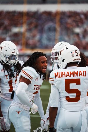 Texas Longhorns football team huddles on sideline during game.