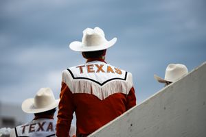 Texas Longhorns band members in cowboy hats stand against a blue sky background.