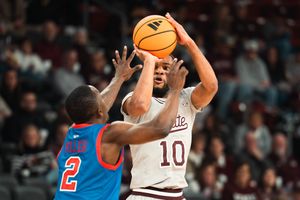 College basketball player #10 shoots over defender #2 during an indoor arena game.