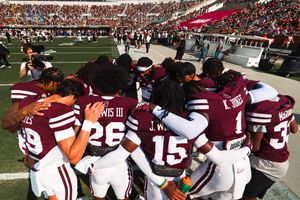 Football team huddled together on the sidelines during a game.