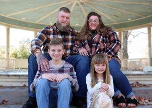 A casual family portrait in matching plaid flannel shirts seated at an outdoor gazebo.