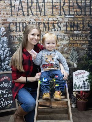 A rustic Christmas photo setup with farm fresh tree signage and festive holiday decorations.