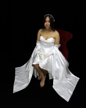 A formal portrait featuring a white satin gown against a black backdrop with elegant poses.