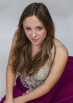 Studio portrait in a sparkly silver and magenta formal gown against gray background.