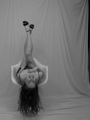 Black and white artistic portrait of someone lying upside down against white backdrop.