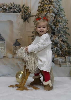A winter holiday scene with white sweater and red pants near decorated Christmas trees and snowy decor.