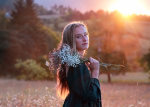 Portrait of woman holding baby's breath flowers in golden sunset light.
