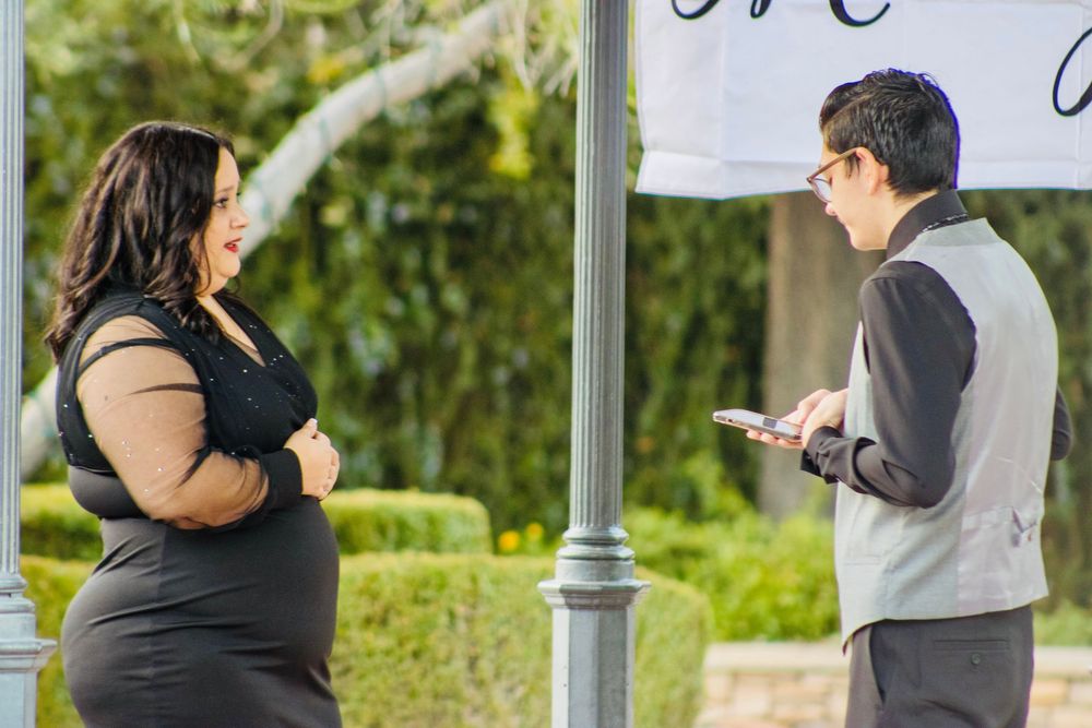 Man and woman having a conversation outdoors near a decorative pole and signage.