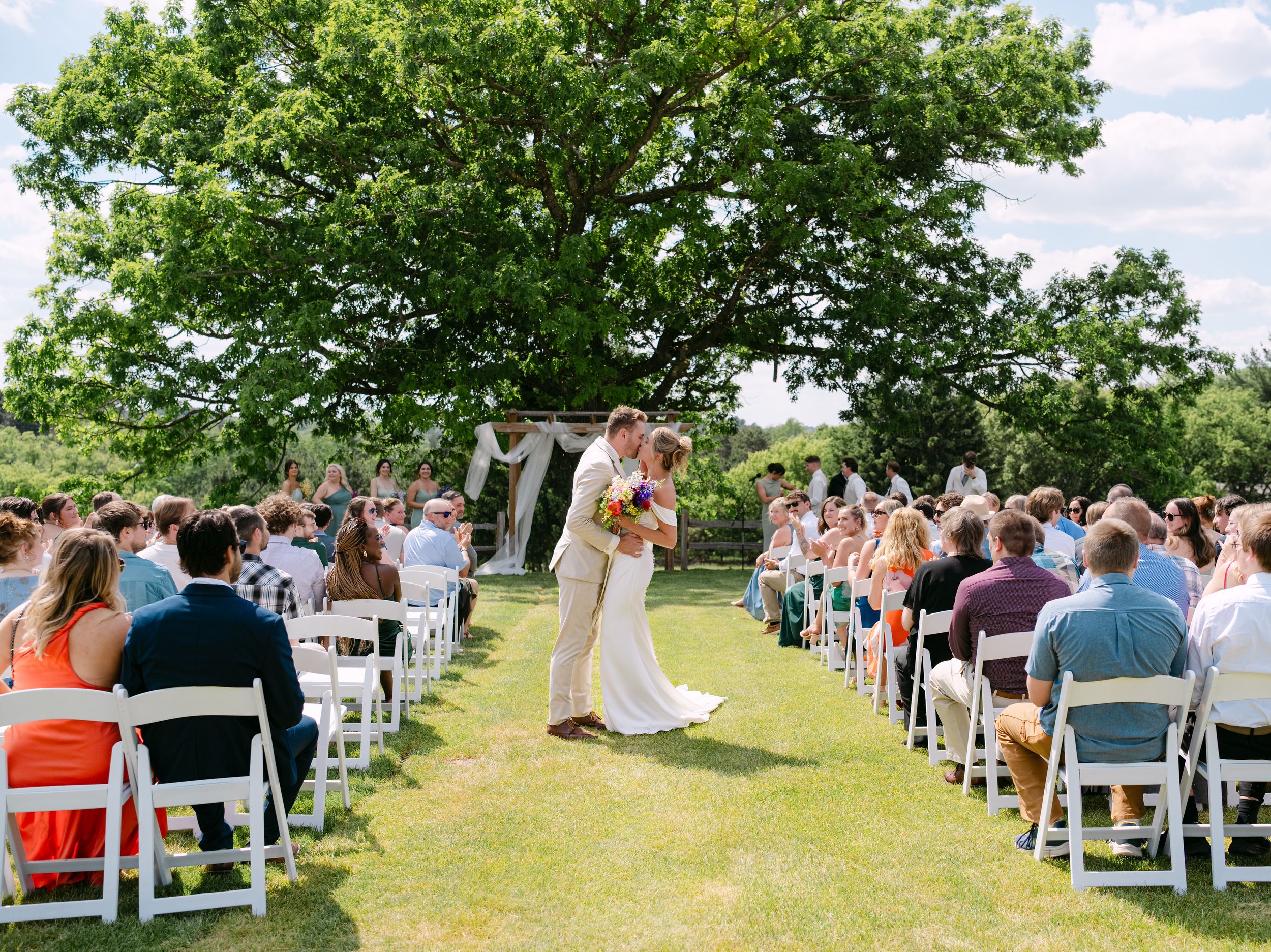 Wedding couple embracing in field with bride's dramatic white dress train.