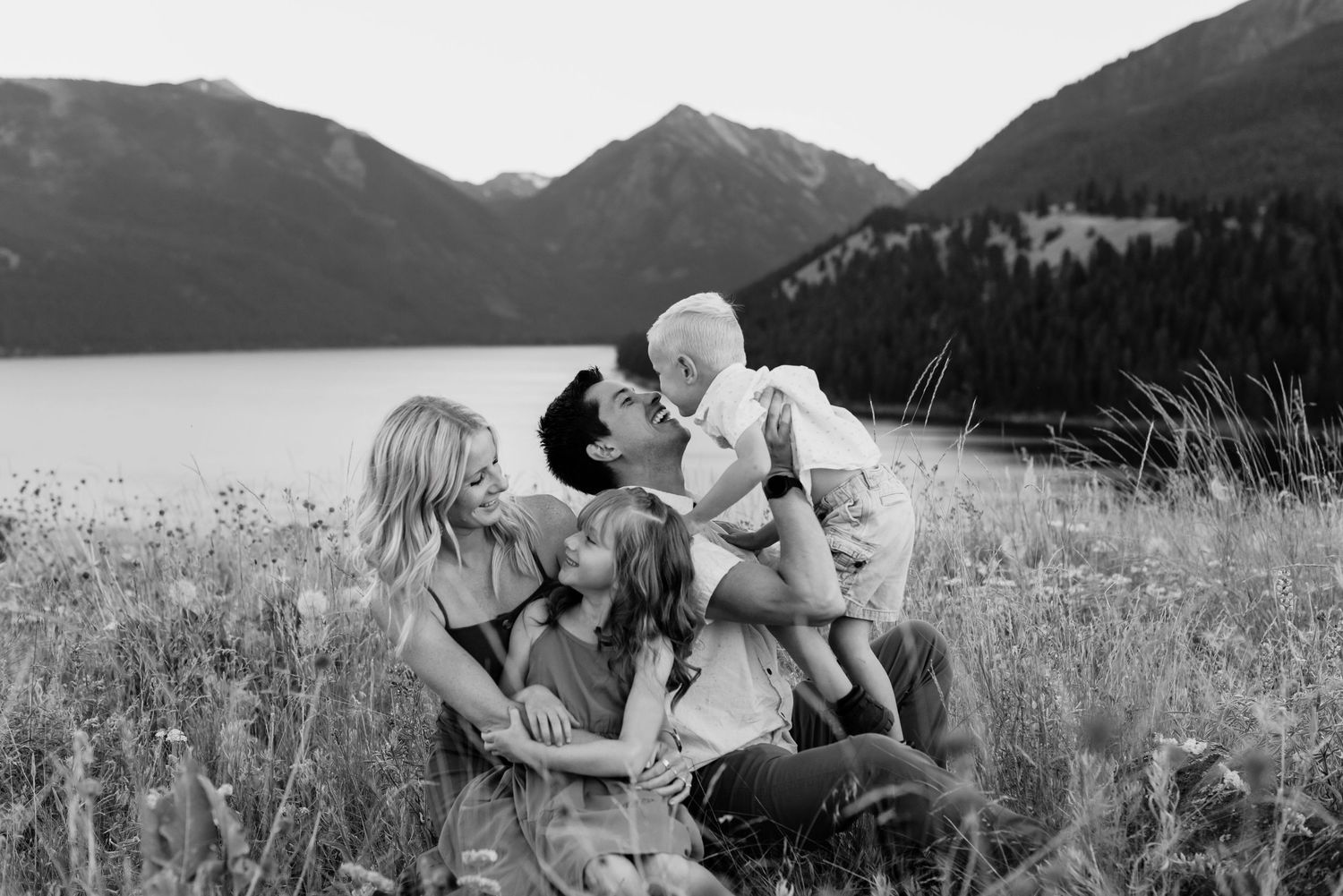 Couple with their kids in front of a mountain lake.