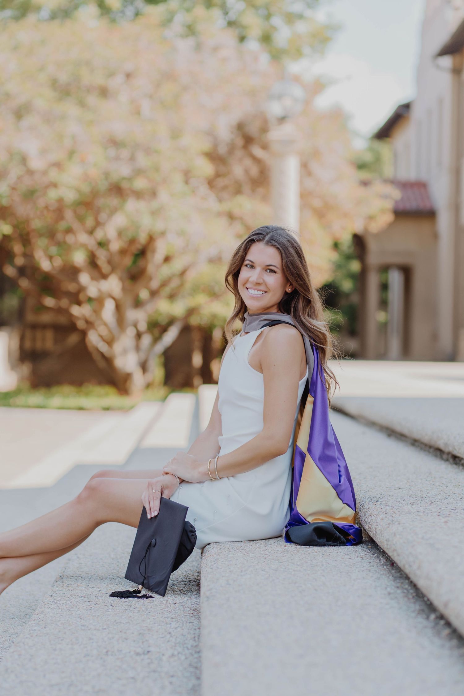 A casual outdoor portrait with white dress and purple backpack on concrete steps.