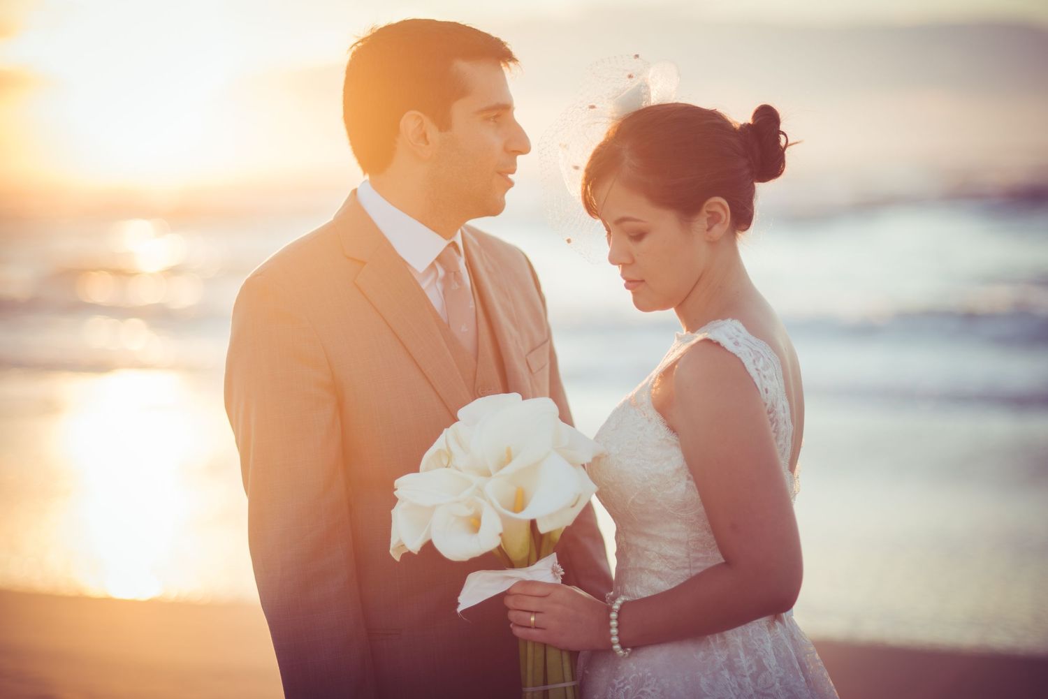 Romantic sunset beach wedding portrait with white bouquet.