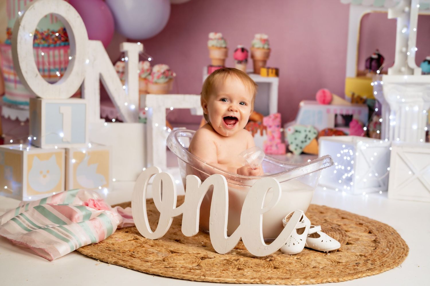 First birthday party scene with balloons and white decorative elements.