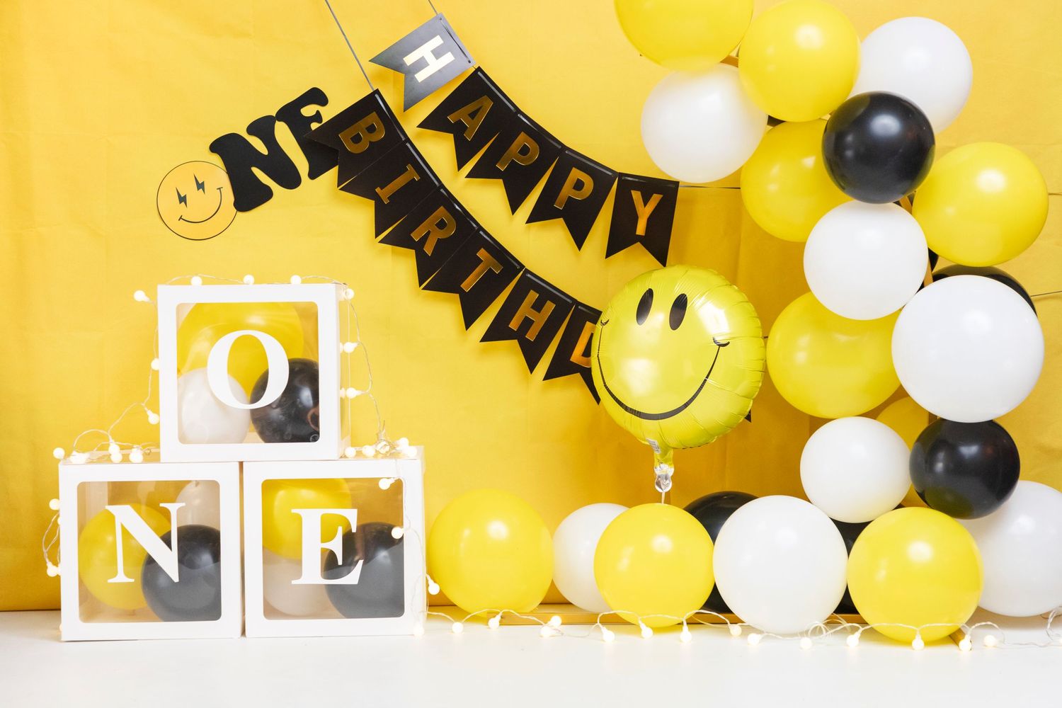 Yellow and black birthday decoration with ONE blocks and smiley face balloons.