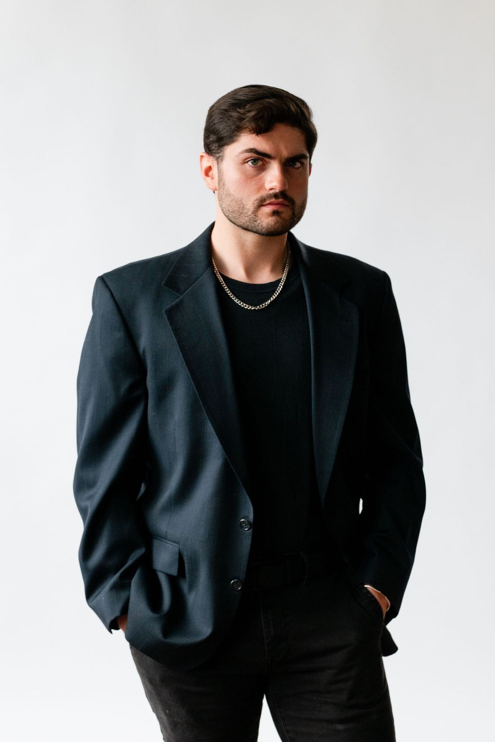 Professional studio portrait of a person in a black blazer and t-shirt against white background.