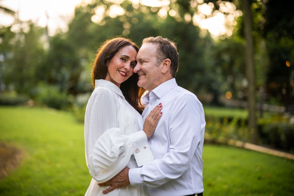 Couple embracing in casual white attire during sunset in a garden setting.