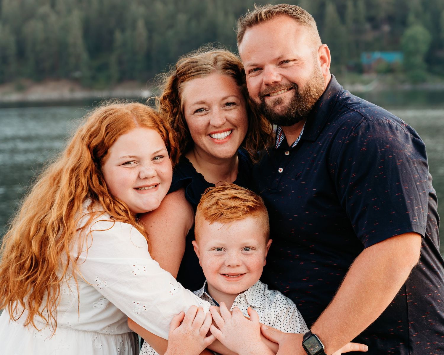 A family of four shares an intimate portrait moment by a lake.  Wallowa Lake, Joseph, Oregon