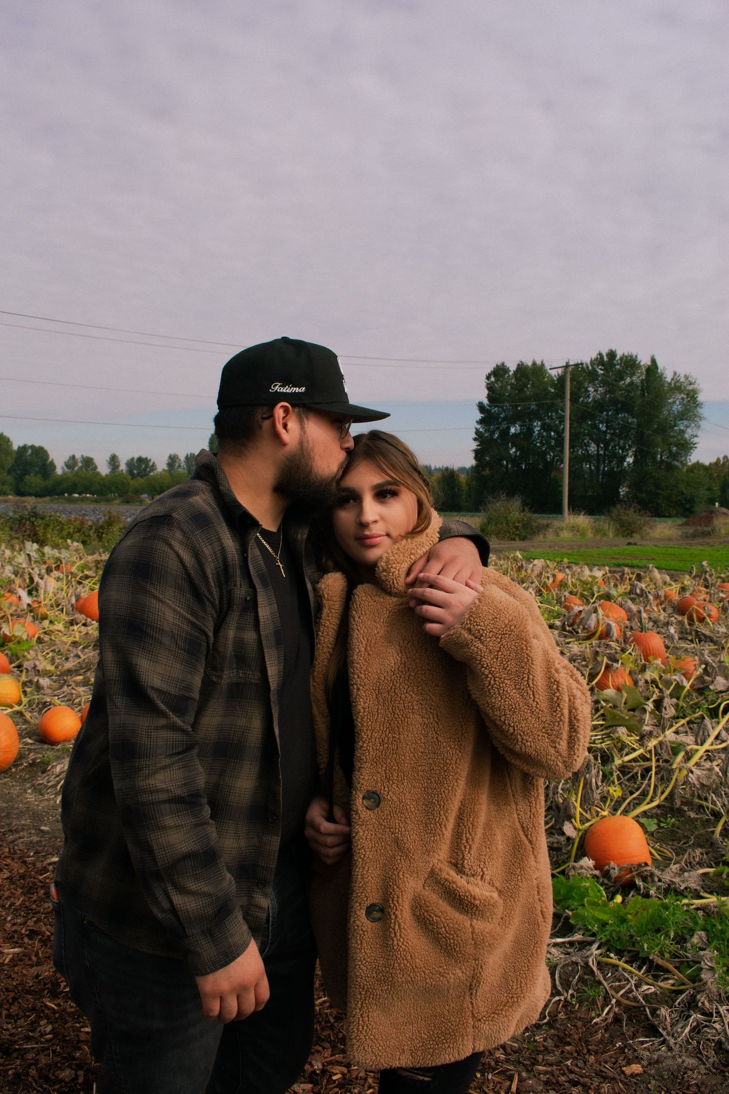 Couple embracing in pumpkin patch during autumn season.