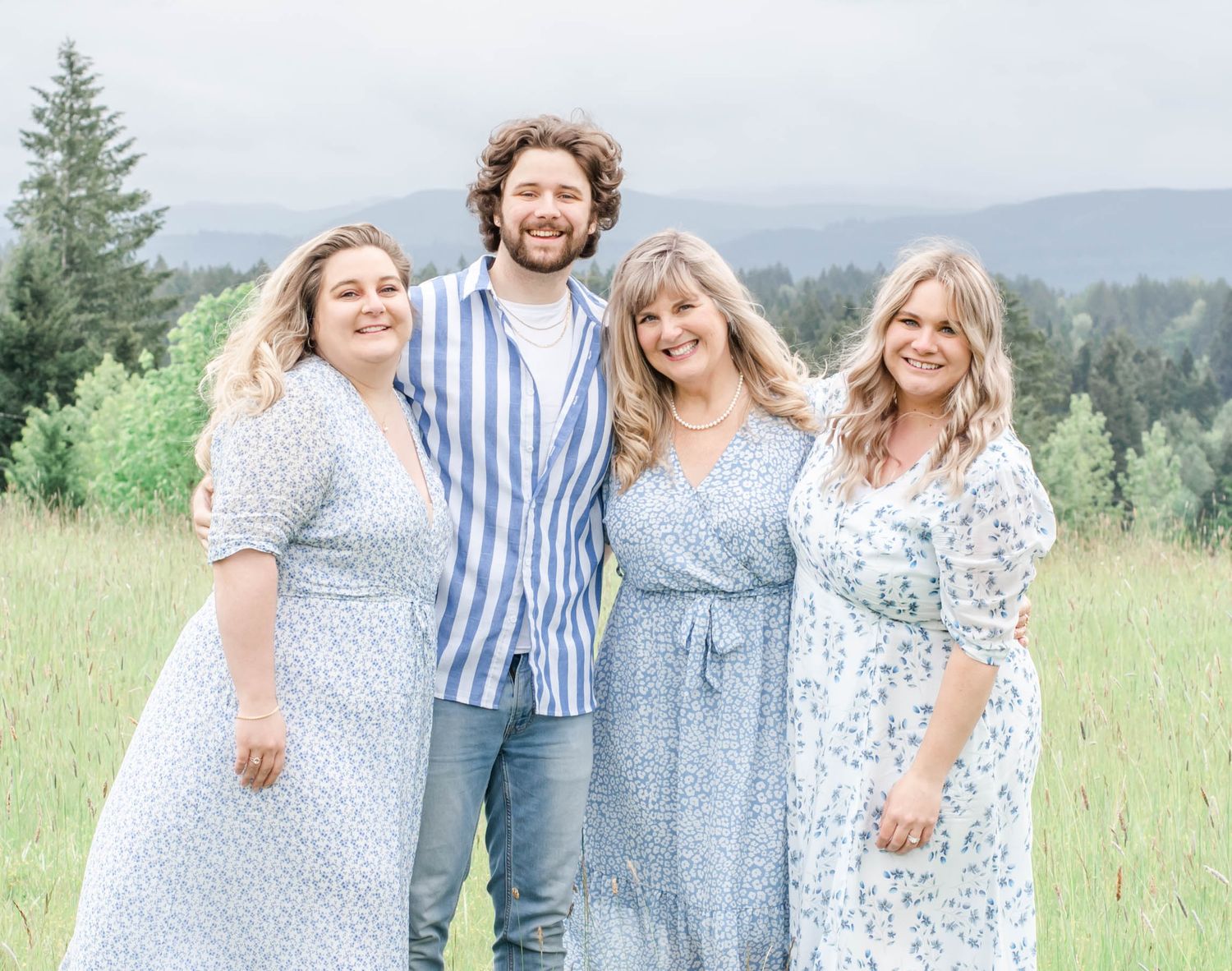 Group poses in coordinating blue and white outfits against a scenic mountain backdrop.