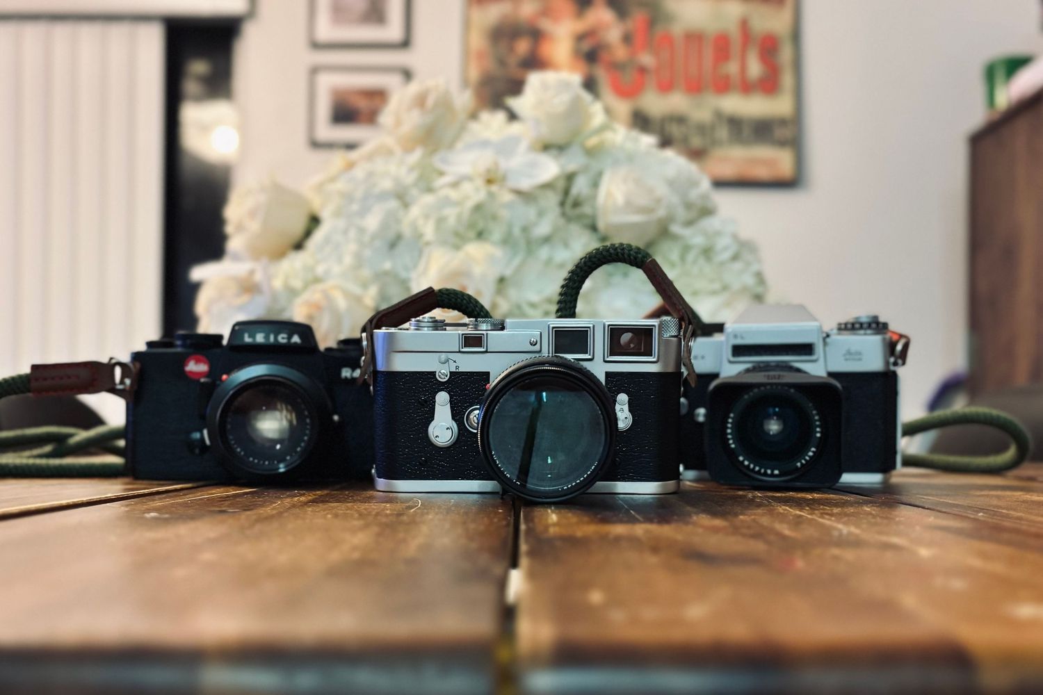 Collection of vintage film cameras lined up on wooden surface.