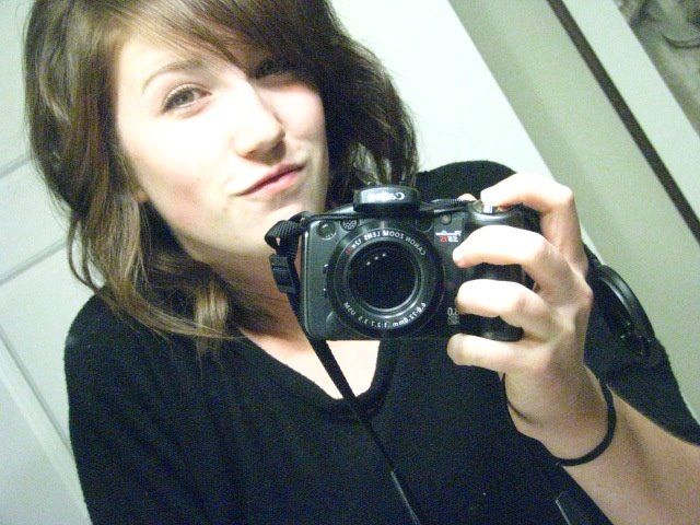 Camera enthusiast taking a mirror selfie with a professional DSLR camera.
