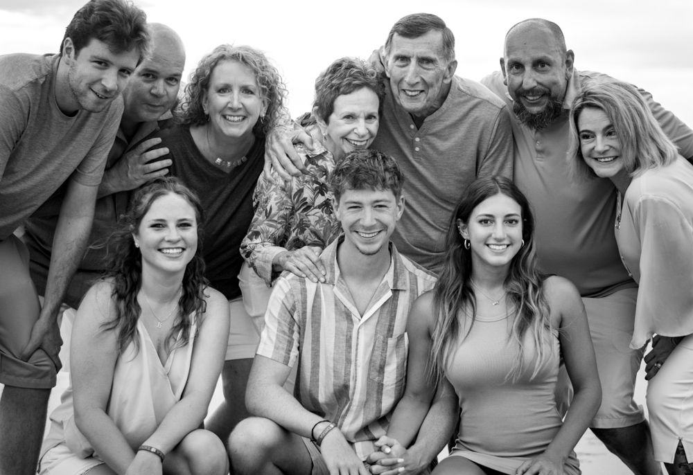 A casual group photo of a family smiling together outdoors in black and white.