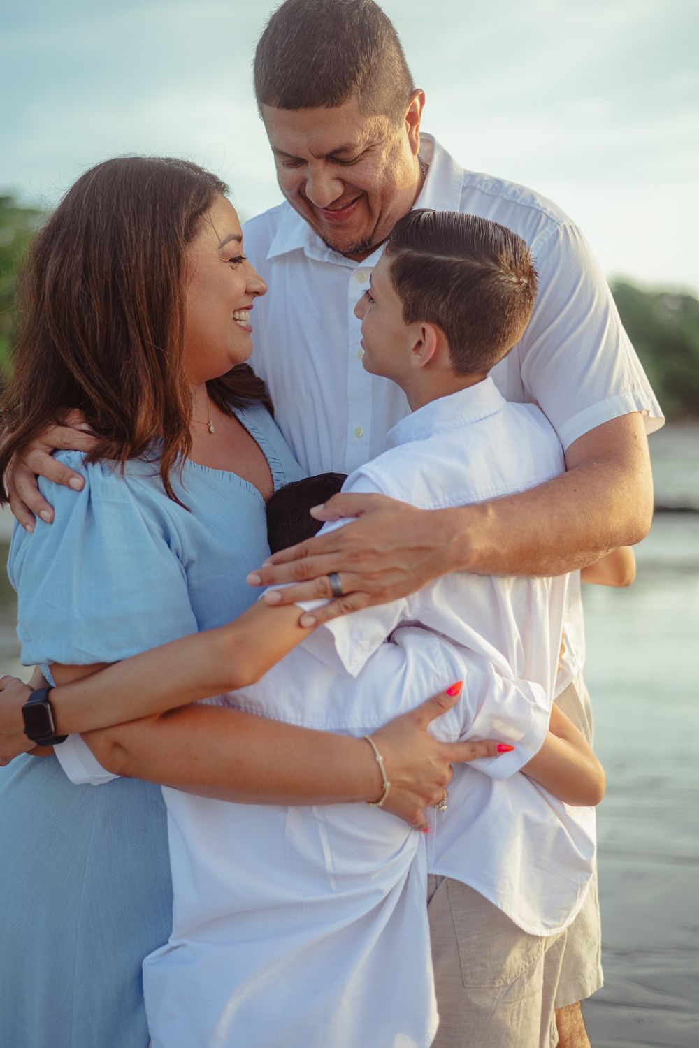 Family of three sharing an intimate moment of laughter by the water.