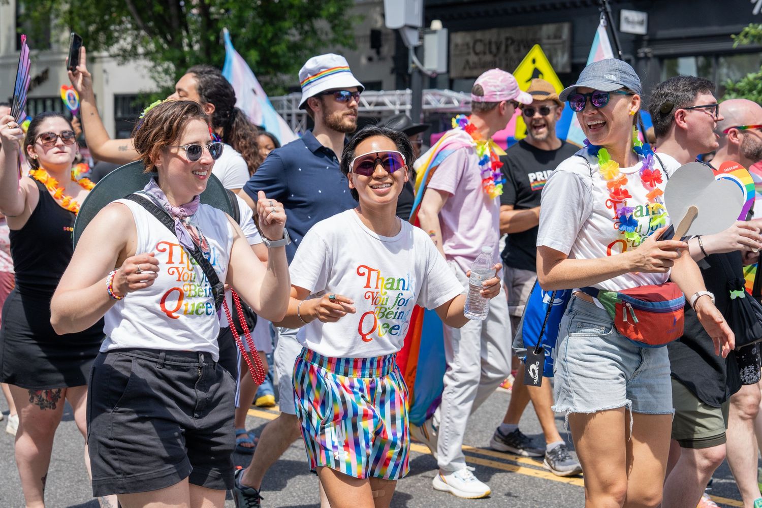 World Pride 2025 in Wash. DC, photo features a group of people smiling in a Pride parade wearing shirts supporting queer and trans people