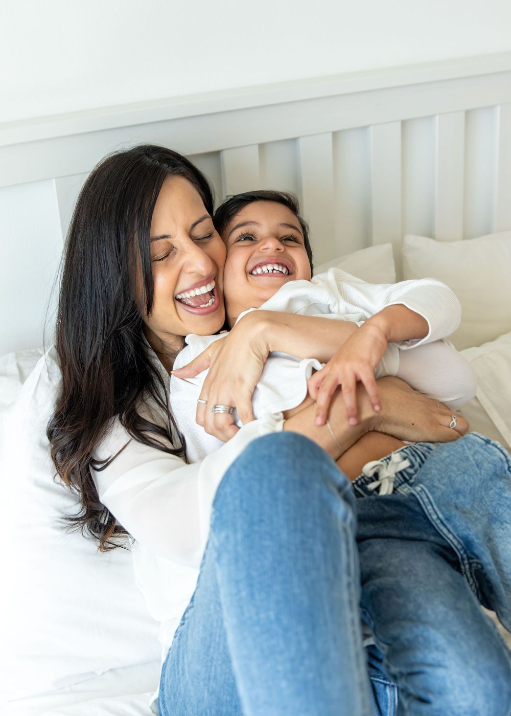 Mother and son laughing and cuddling on the master bed in Dubai in candid shot taken during an at-home photoshoot in Dubai