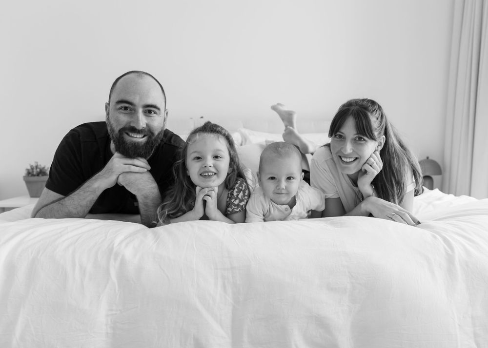 Black and white photos of young family on master bed during an at-home family photoshoot in Dubai by Carlene Thurston Photography