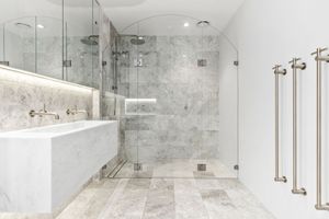 Modern bathroom interior with marble walls, glass shower enclosure, and brushed nickel fixtures in a luxurious design.