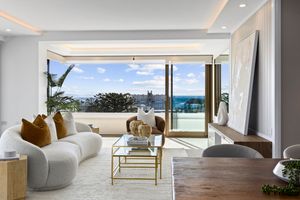Luxurious beachfront apartment interior showcasing modern furniture and panoramic ocean views through floor-to-ceiling windows.