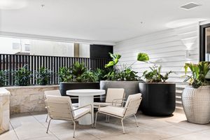 Modern minimalist office interior with sleek white furniture, glass partitions, and indoor plants creating a bright workspace.