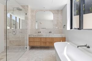 Modern white marble bathroom interior with glass shower enclosure, floating vanity, and chrome fixtures.
