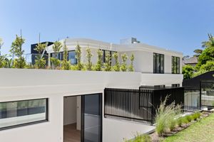 Modern luxury home exterior features sleek black and white design with vertical slat details and landscaped garden.