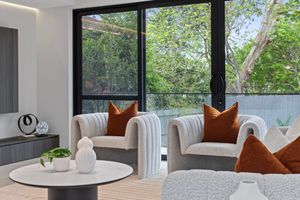 Modern living room interior with panoramic windows, white walls, and brown accent pillows features ambient lighting.
