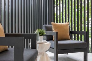 Modern outdoor patio with vertical slat privacy screens, dark furniture, and neutral cushions in a contemporary setting.