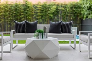 Modern outdoor patio furniture with gray cushions and sleek white planters arranged around a contemporary seating area.