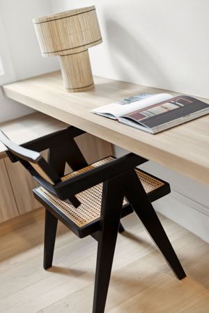 Modern bench design featuring black X-shaped legs and woven cane seat with a minimalist light wood top surface.