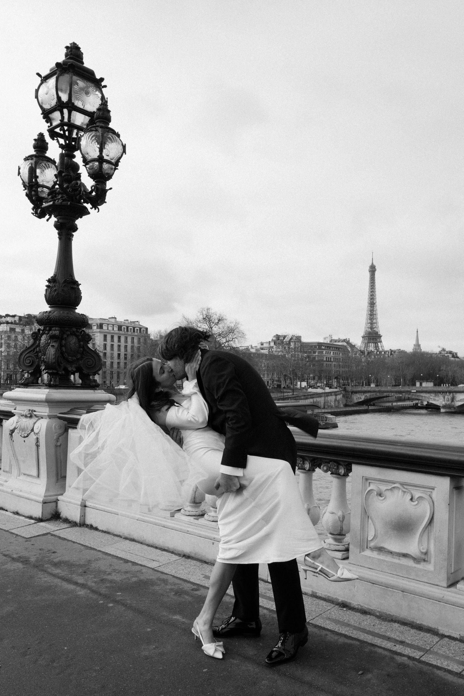 A romantic black and white photo at Pont Alexandre III bridge with the Eiffel Tower visible in Paris.