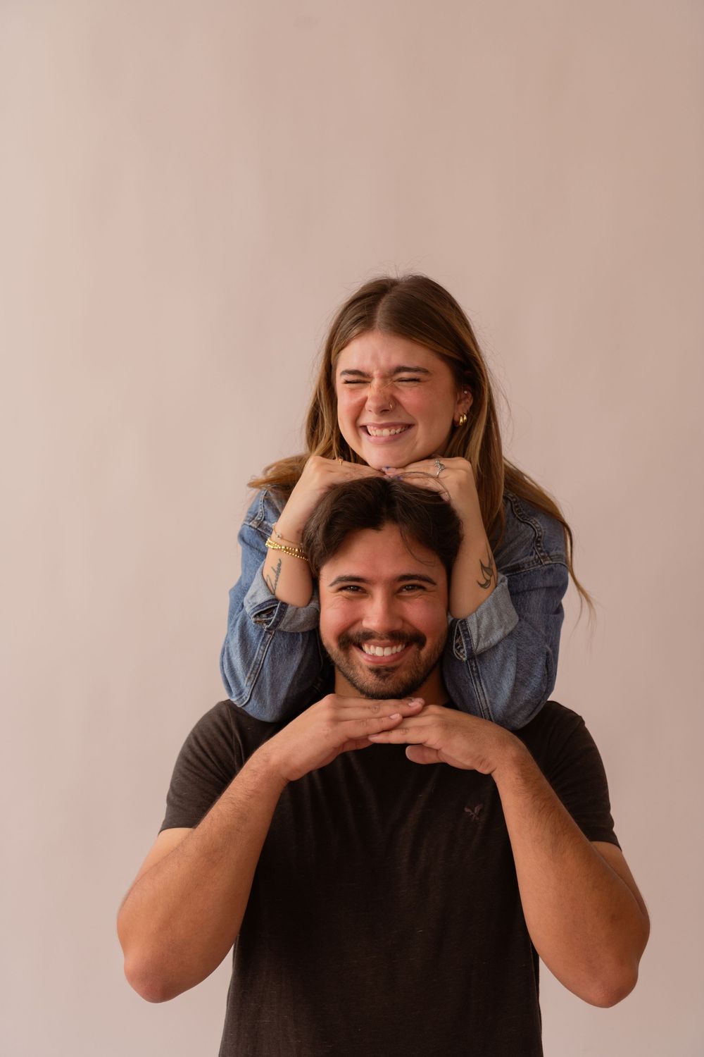 Smiling woman resting chin on mans head while sitting on his shoulders.