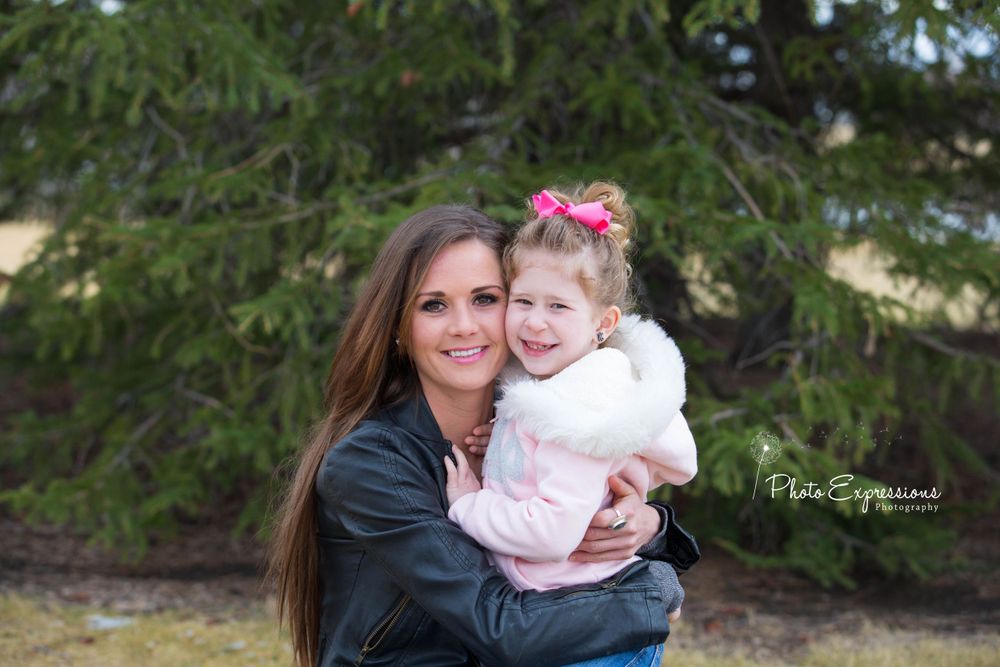 Tender family moment captured under evergreen trees.